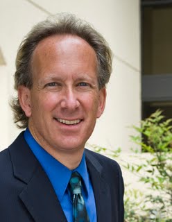Professional headshot of Steve Zikman, California Bar Exam expert tutor, attorney, and former Administrative Law Judge, smiling in a navy suit and blue shirt.