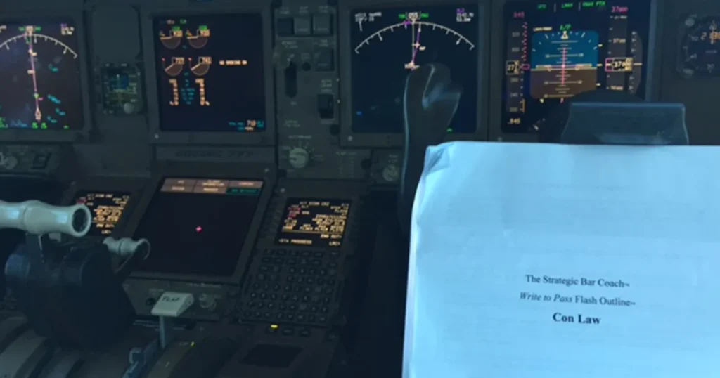A pilot studying a Strategic Bar Coach Con Law outline inside an airplane cockpit, demonstrating how to fit in micro-study sessions for bar prep while working full time.